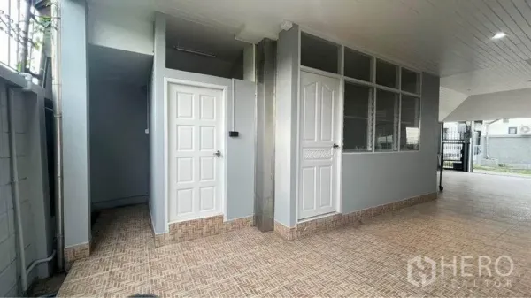 Detached House for rent in Bang Kapi, Bangkok - Covered utility area with tiled flooring, two white doors and side windows next to the parking space.