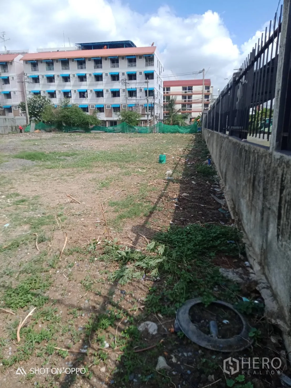 Land for rent in Khan Na Yao, Bangkok - Narrow side strip of bare earth along a concrete wall and fence within the plot.