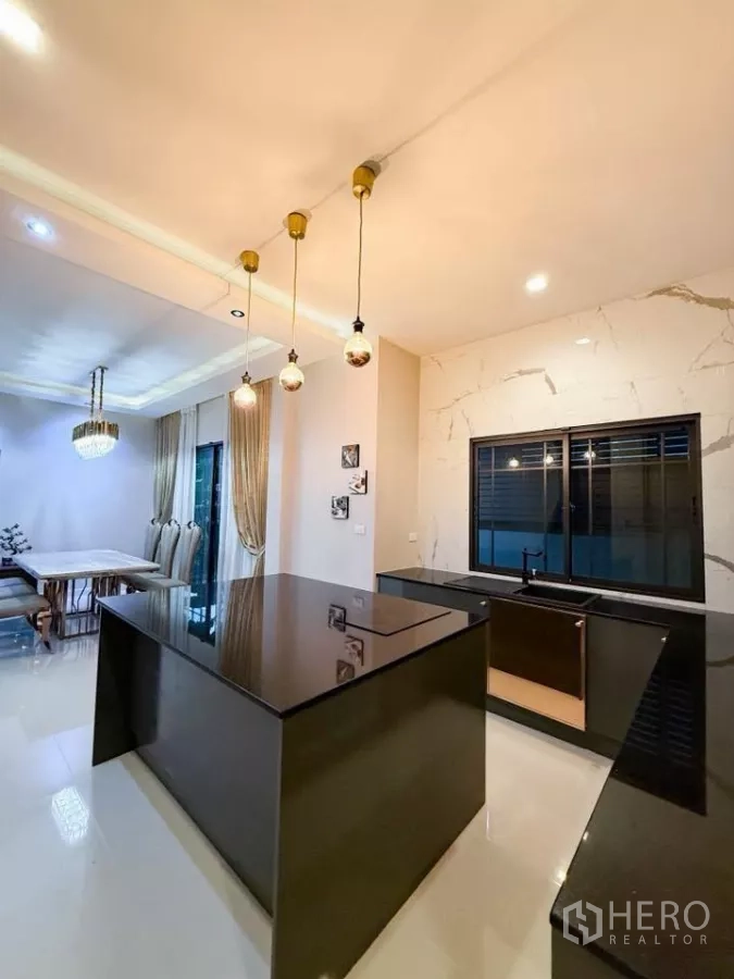 Detached House for rent or sale in Bang Phli, Samut Prakan - Kitchen island lighting with pendant lamps facing the dining area and black granite counters.