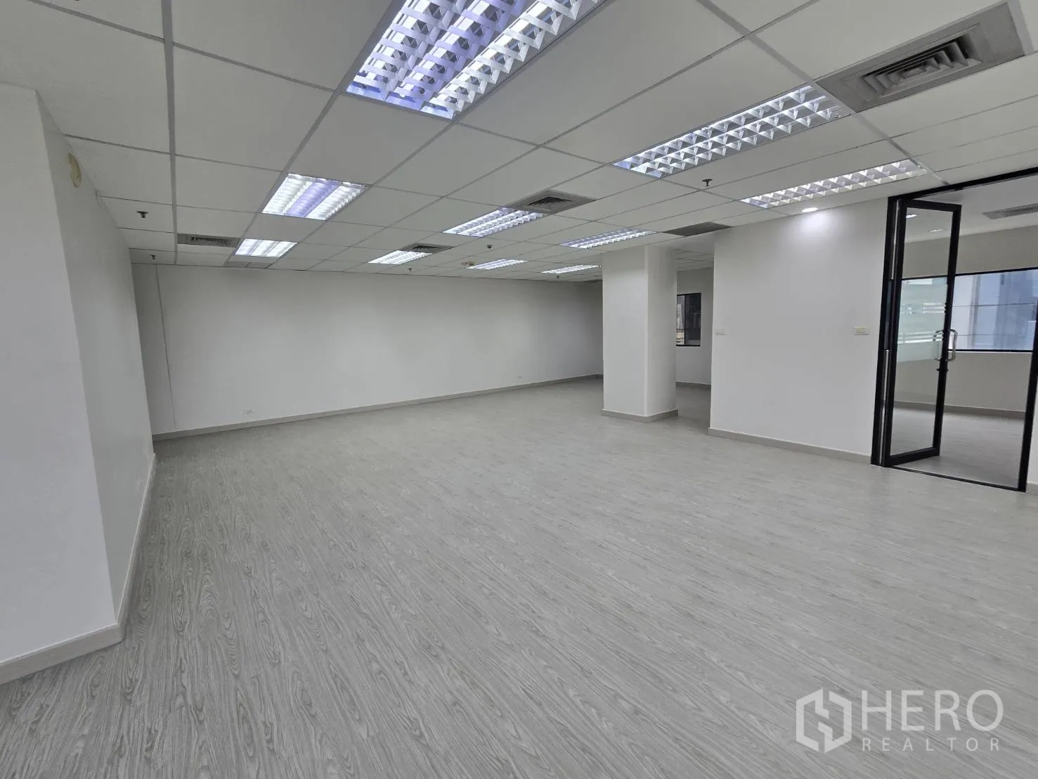 Office Space for rent in Khlong Toei, Bangkok - Expansive office zone with bright ceiling lights and a glass entry door.