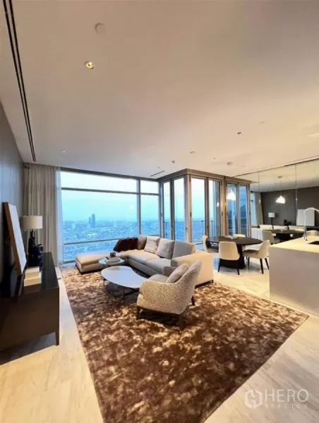 Condominium for rent in Sathon, Bangkok - Open-plan living and dining room with floor-to-ceiling windows and panoramic Bangkok skyline at dusk.