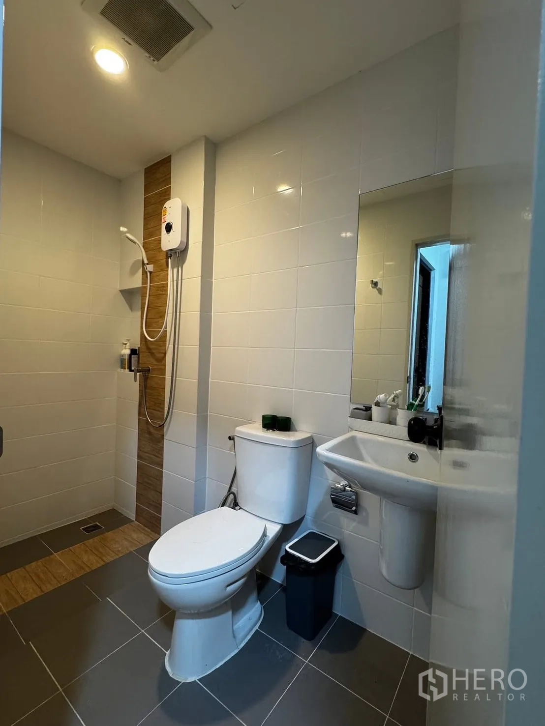 Townhouse for rent in Bang Phli, Samut Prakan - Tiled bathroom featuring a shower with water heater, toilet, and pedestal sink.