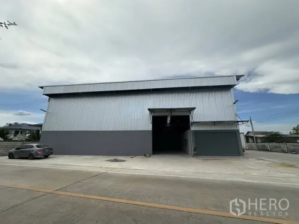 Warehouse for rent in Sai Noi, Nonthaburi - Modern corrugated steel warehouse exterior with roller door and driveway in Sai Noi, Nonthaburi.