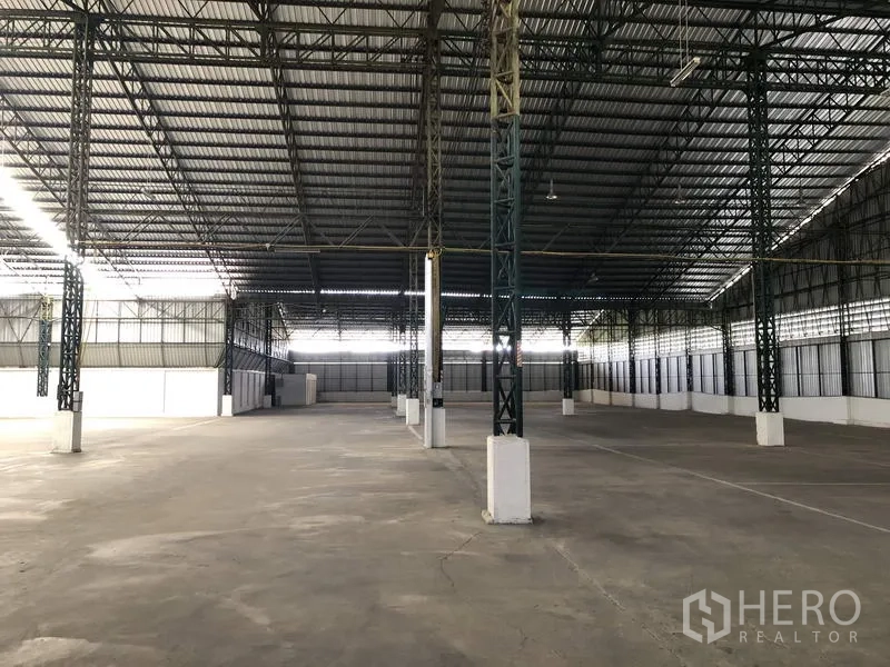 货栈 出租在Mueang Pathum Thani, Pathum Thani - 巴吞他尼直辖县宽敞仓库内部，高钢结构桁架屋顶、宽柱距与平整混凝土地面。
