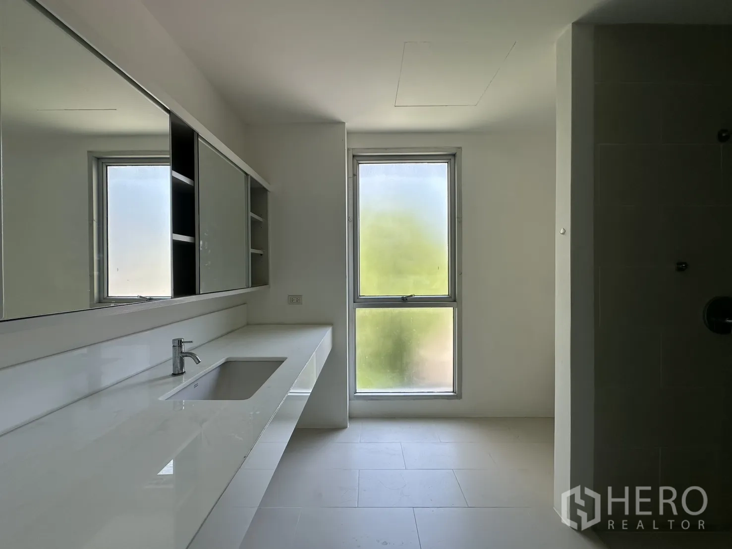 Home Office for rent in Phra Khanong, Bangkok - Bright bathroom with a long vanity, mirror cabinets, and a frosted window.