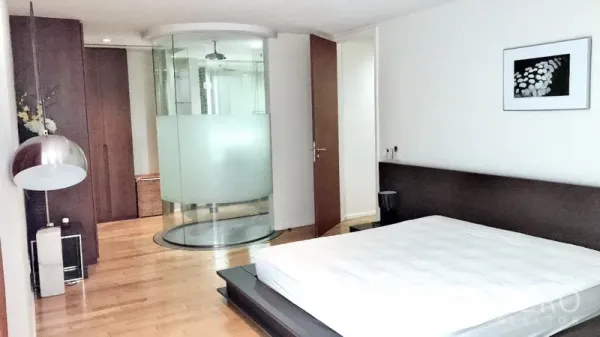 公寓 出租在Bang Rak, Bangkok - 主卧配平台床、内置衣柜与弧形玻璃淋浴间。