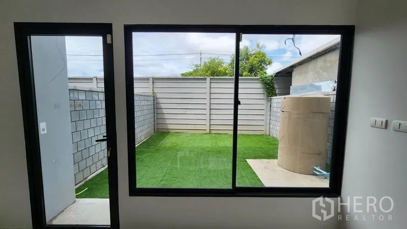 สำนักงานที่บ้าน ให้เช่า - มุมมองสู่ลานหลังบ้านปูหญ้าเทียมผ่านประตูกระจก