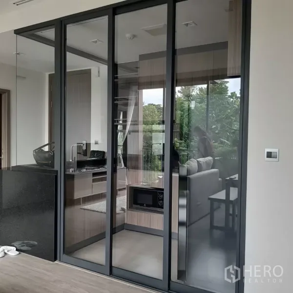 คอนโด ให้เช่าในWatthana, Bangkok - ผนังกระจกบานเลื่อนกั้นครัวกับห้องนั่งเล่น สะท้อนวิวสีเขียวภายนอก