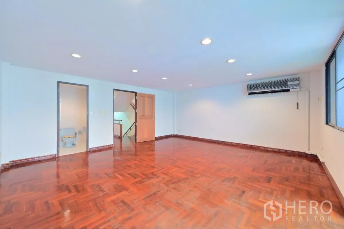 Townhouse for sale in Watthana, Bangkok - Large bedroom with parquet floor, built-in air conditioner, and ensuite access.