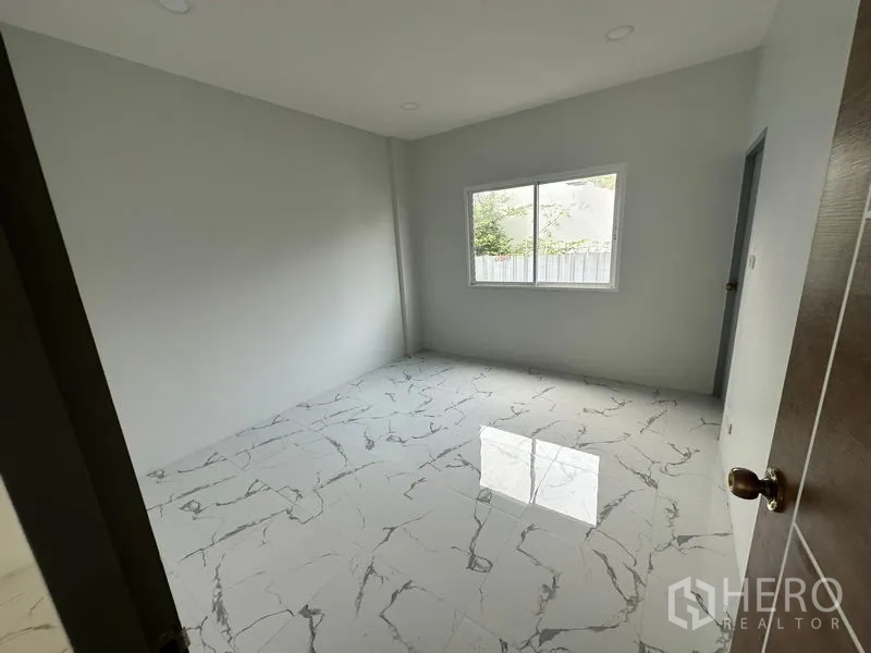 Home Office for rent or sale - Simple bedroom with marble-look floors and a window facing greenery.