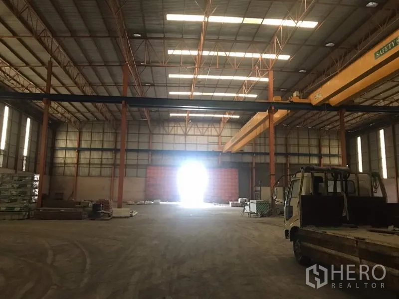Home Office for sale in Khlong Luang, Pathum Thani - Interior bay with a truck parked beneath overhead cranes and bright end door.