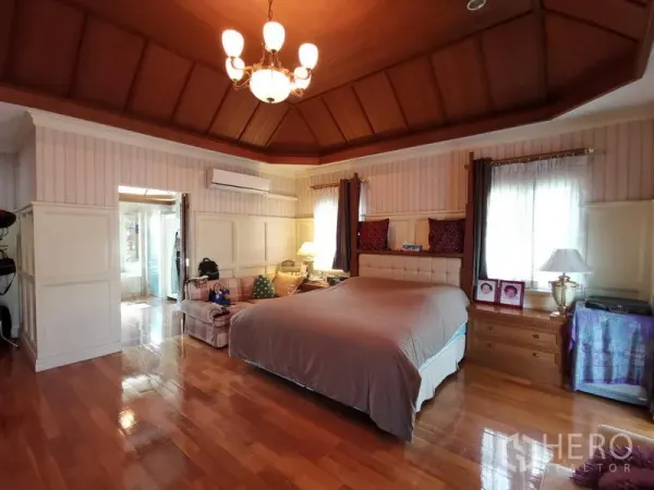独立式住宅 出售在Phra Khanong, Bangkok - 主卧带木质托盘天花与吊灯，空间开阔。