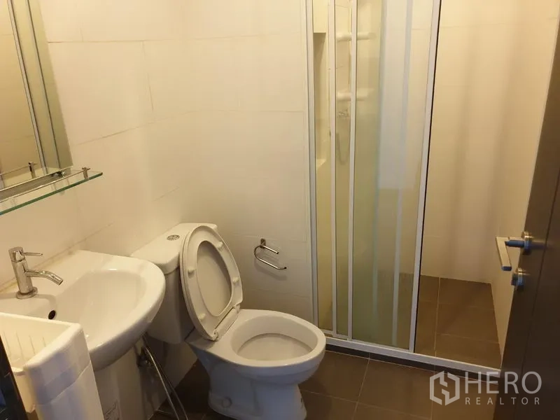 Condominium for rent in Watthana, Bangkok - Bathroom with basin, toilet, and glass-enclosed shower area.