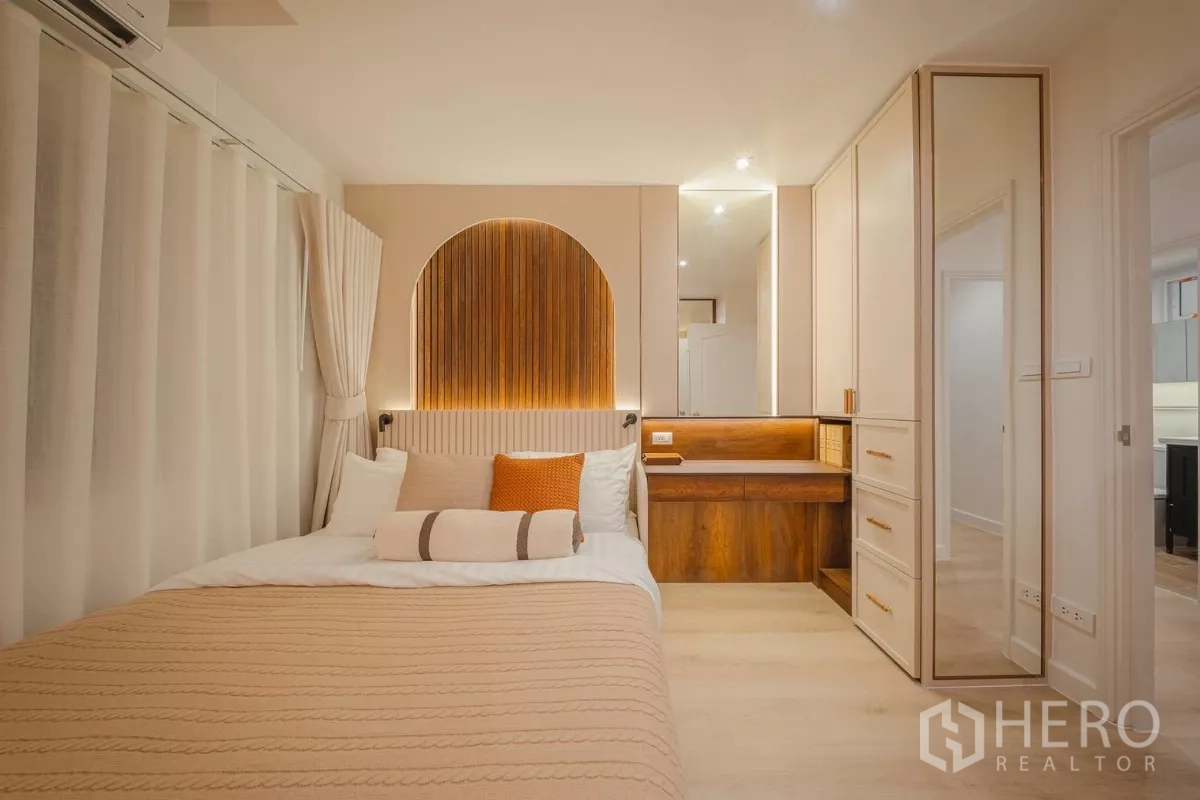 Condominium for rent in Yan Nawa, Bangkok - Bedroom front view with arched wood panel headboard, dressing table and wardrobes.