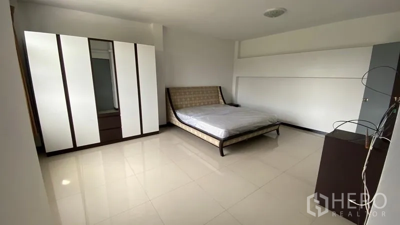 联排别墅 出租在Bang Na, Bangkok - 卧室另一角度，展示床、衣柜与中性色地砖。