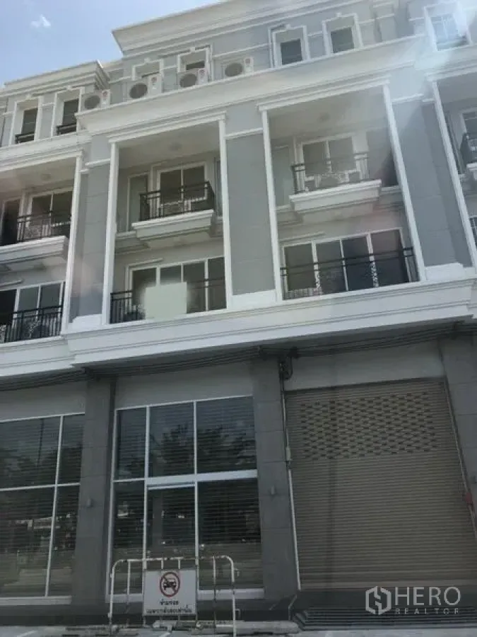 店屋 出租在Bang Na, Bangkok - 现代多层店屋外观，玻璃店面与阳台及卷帘门，位于邦那。