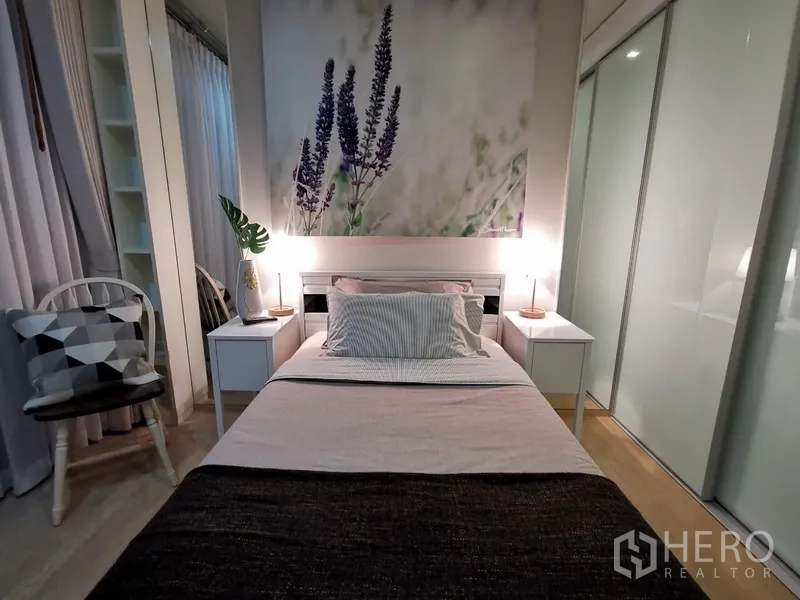 公寓 出售在Bangkok - 次卧设单人床、薰衣草装饰画、椅子与推拉衣柜门。