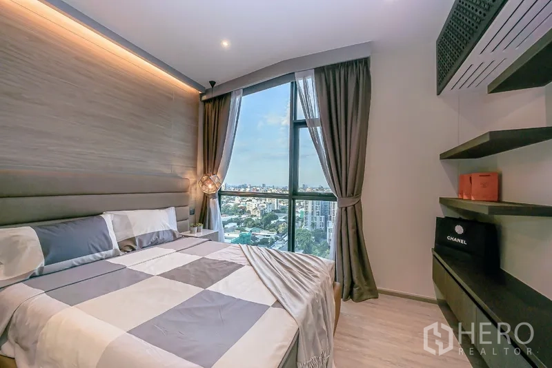Condominium for rent in Watthana, Bangkok - Cozy second bedroom with tall window, shelves, and wide city view.
