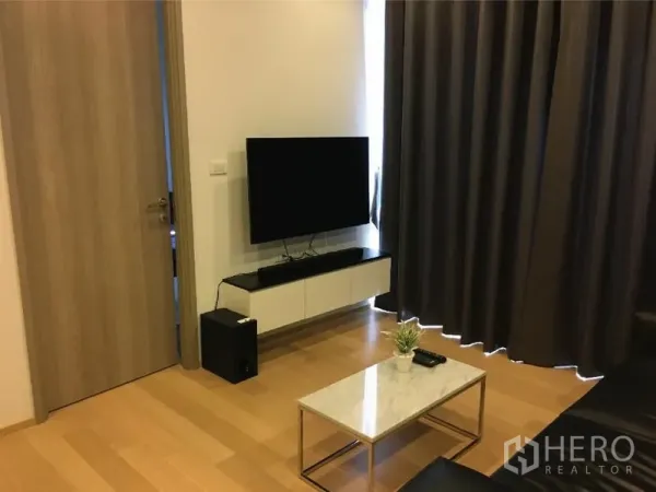 คอนโด ให้เช่าหรือขายในWatthana, Bangkok - พื้นที่นั่งเล่นพร้อมตู้ทีวีติดผนัง โต๊ะกลางหินอ่อน และผ้าม่านสูงจรดพื้น.