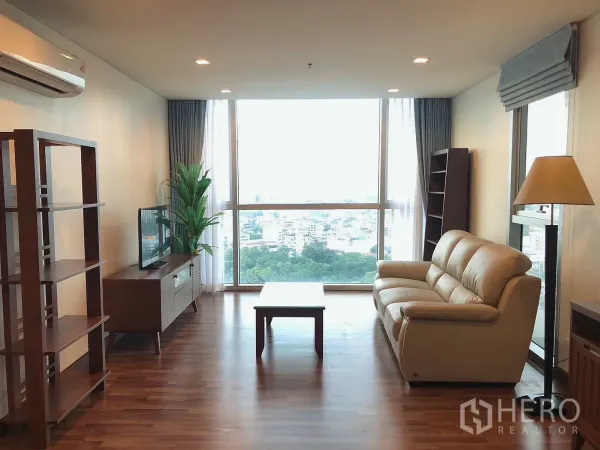 คอนโด ให้เช่าในKhlong Toei, Bangkok - ห้องนั่งเล่นสว่างด้วยหน้าต่างเต็มผนัง พื้นไม้ โซฟาหนัง และวิวเมืองกรุงเทพกว้างไกล