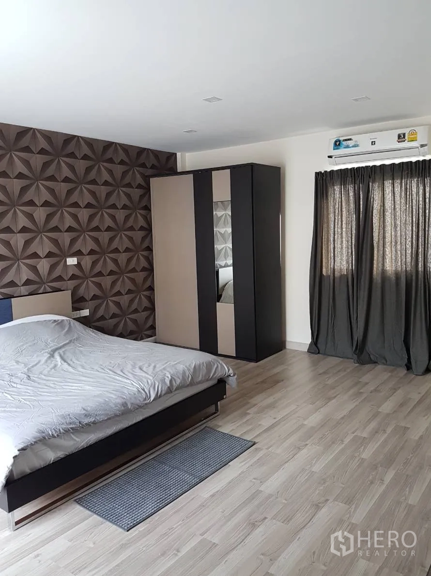 Townhouse for rent or sale in Saphan Sung, Bangkok - Spacious master bedroom with wood flooring, feature wall, wardrobe and air conditioning.