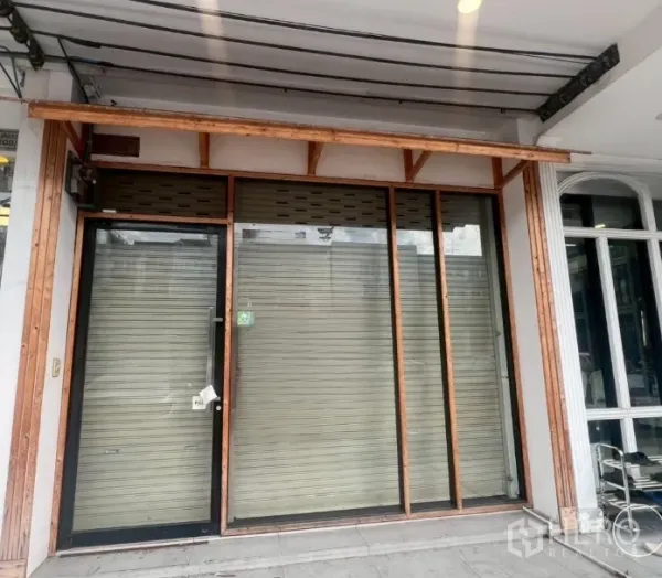 店屋 出租 - 一层店面，玻璃门、金属卷闸与木质雨篷。