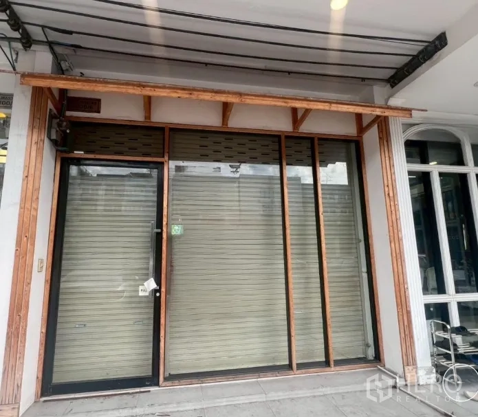 店屋 出租 - 一层店面，玻璃门、金属卷闸与木质雨篷。