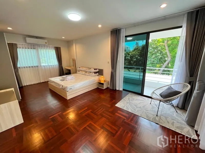 独立式住宅 出租在Phaya Thai, Bangkok - 宽敞卧室，木地板，落地阳台门与休闲椅。