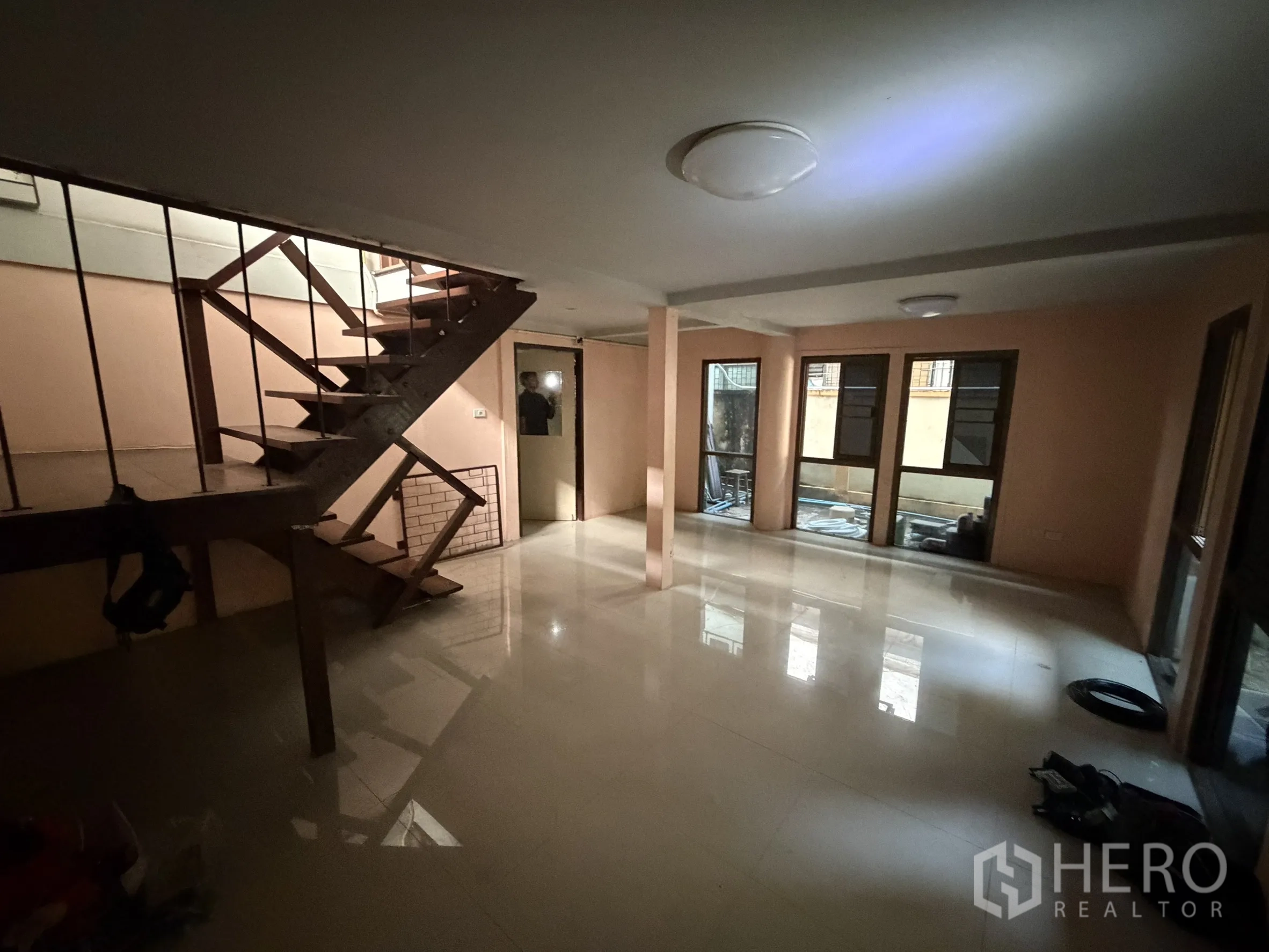 Shophouse for rent in Sathon, Bangkok - Open‑plan ground floor with tiled flooring, windows and a wooden staircase.