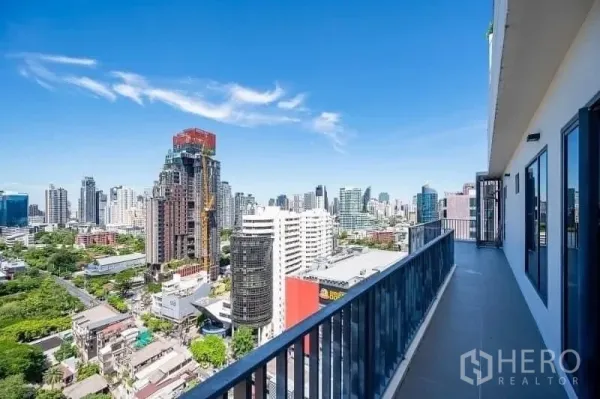 公寓 出售 - 带栏杆的长阳台，俯瞰曼谷天际线与蓝天白云。