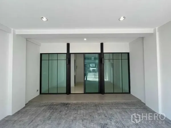 Home Office for rent - Covered parking area leading to black-framed glass sliding doors at the building entrance.