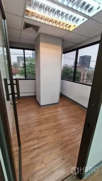 Office Space for rent in Watthana, Bangkok - Compact corner room with wraparound windows and a glass door.