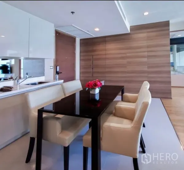 公寓 出租在Bang Rak, Bangkok - 现代用餐区，黑色亮面餐桌、米色座椅与开放式厨房