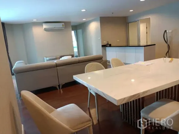 Condominium for rent or sale in Huai Khwang, Bangkok - Open-plan living and dining area with marble table, L-shaped sofa and wood floors.