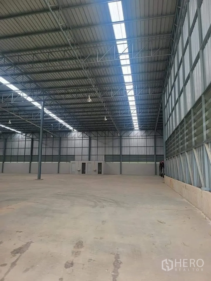 仓库 for rent in Lat Krabang, Bangkok - 面向端墙的室内景观，挑高天花、天窗带与功能房间。