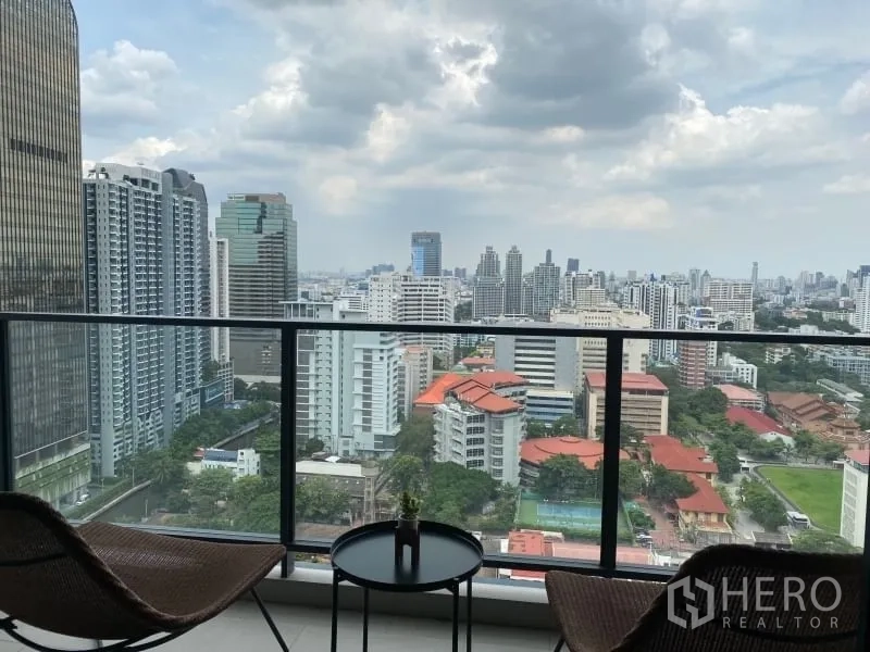 คอนโด ให้เช่าหรือขายในWatthana, Bangkok - ระเบียงแบบมีหลังคา เก้าอี้สองตัวและโต๊ะเล็ก มองเห็นวิวเมืองและพื้นที่สีเขียว