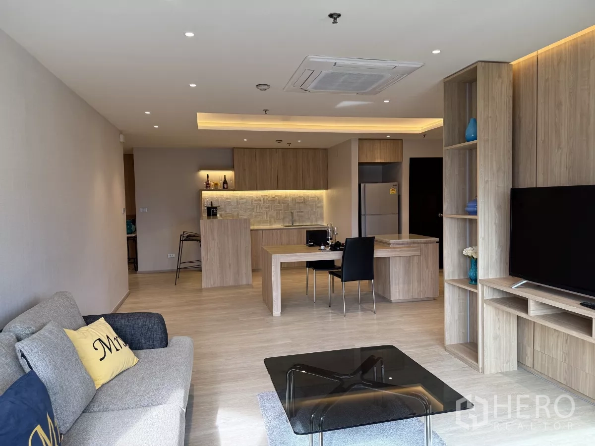 คอนโด ให้เช่าในWatthana, Bangkok - ห้องนั่งเล่นกว้างเชื่อมครัว มีโต๊ะทานอาหาร ไฟฝ้าซ่อนแสง ตู้ครัวโทนไม้ และโซฟาเซ็ต.