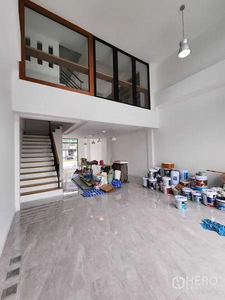 带办公室的家 出租在Prawet, Bangkok - 现代商住两用办公楼的挑高大堂与夹层，楼梯与亮面瓷砖地面，正在轻度整修。