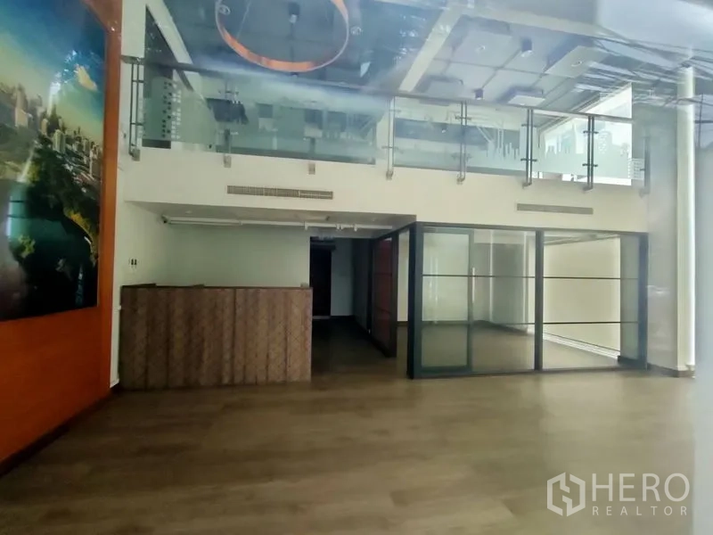 办公空间 出租在Pathum Wan, Bangkok - 阁楼风格办公内景，带夹层、玻璃扶手、木地板、接待台和玻璃隔断会议室