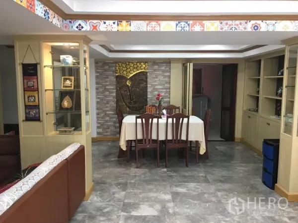 Townhouse for rent in Khlong Toei, Bangkok - Open‑plan dining area with six‑seat table, built‑in display cabinets and patterned ceiling trim.