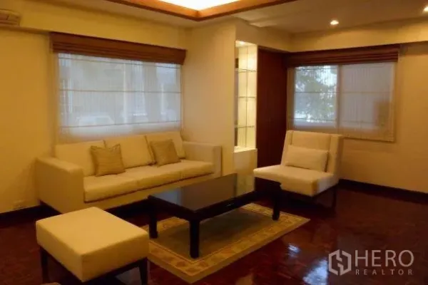 Condominium for rent in Pathum Wan, Bangkok - Cozy living room with cream sofa set, coffee table, recessed lighting, and corner windows.