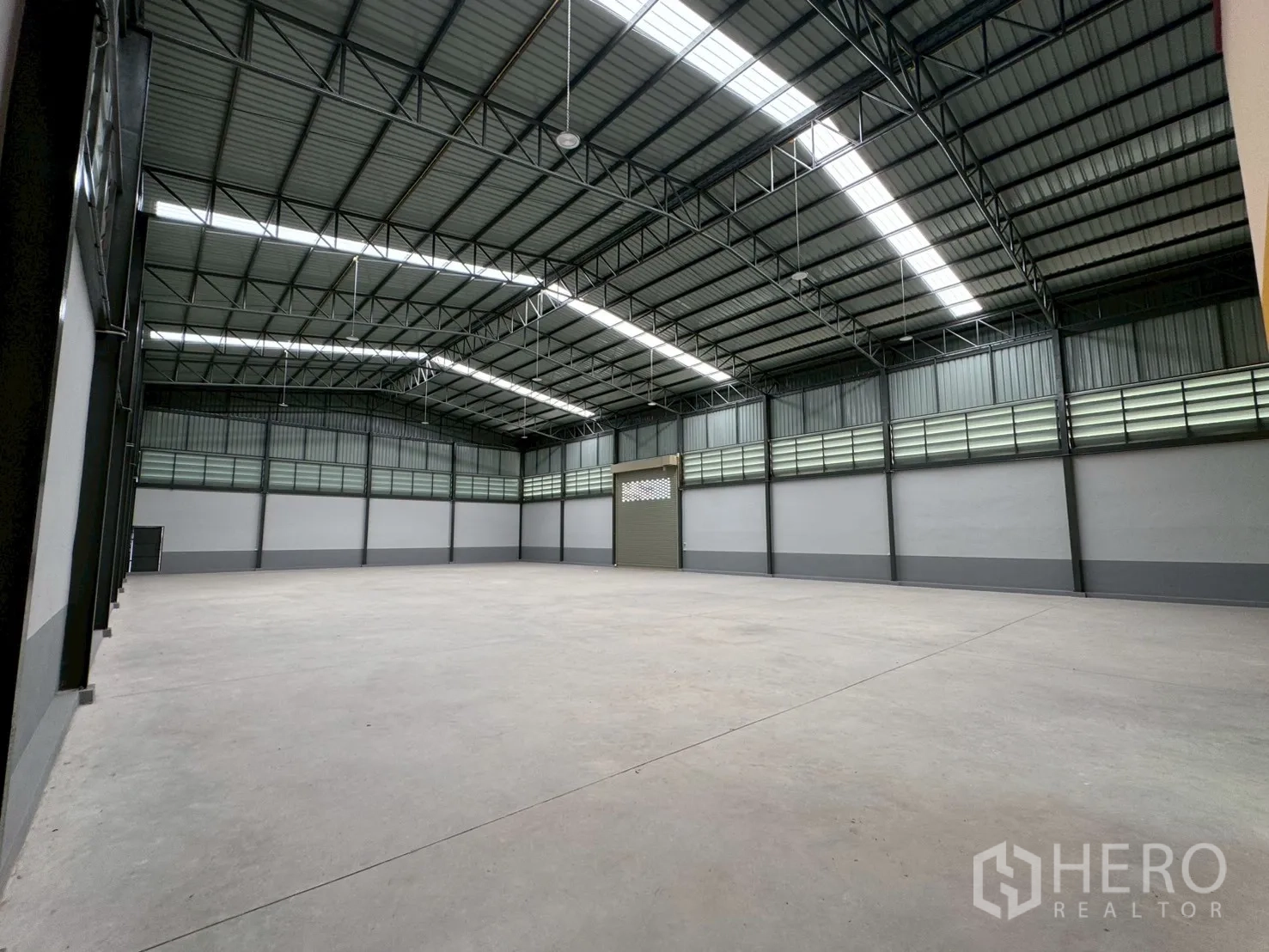 工厂 for sale in Mueang Samut Sakhon, Samut Sakhon - 挑高仓库大厅，钢桁架屋顶与采光板。