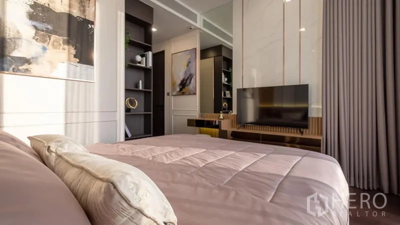 Condominium for rent in Watthana, Bangkok - Spacious bedroom featuring wall-mounted TV, open shelving, and neutral decor.