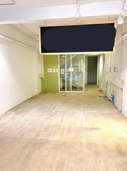 店屋 出租在Phaya Thai, Bangkok - 一层开放式空间，水泥地面、白色墙面与玻璃隔断通往楼梯