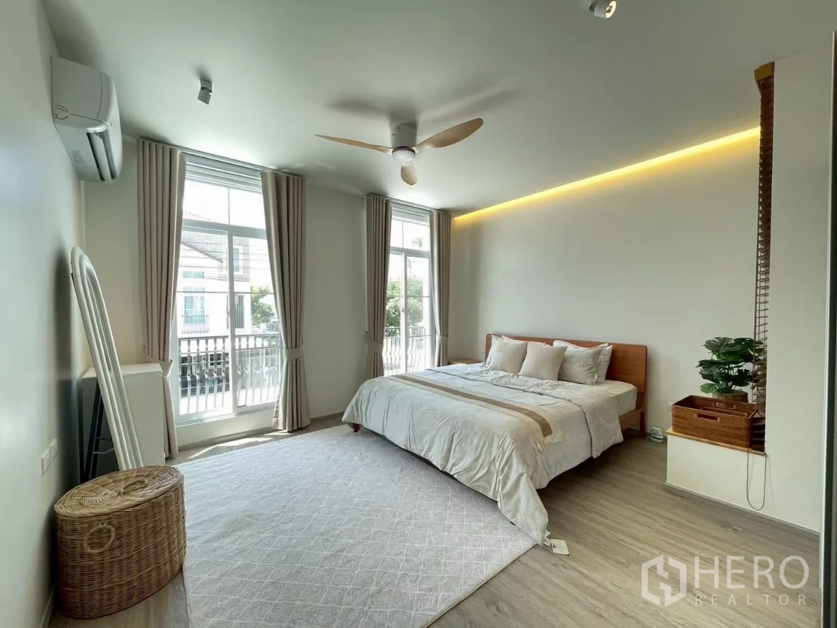 联排别墅 出租在Prawet, Bangkok - 宽敞卧室，双落地窗，带阳台与特大床。