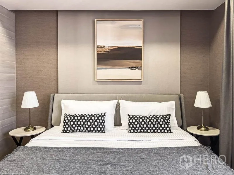 Condominium for rent in Pathum Wan, Bangkok - Cozy bedroom with a king bed, twin bedside lamps, and framed artwork above the headboard.