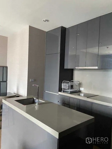 Condominium for sale in Bang Rak, Bangkok - Sleek grey kitchen with island countertop, glossy cabinets and built‑in appliances.