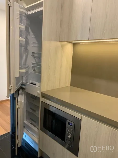 Condominium for sale in Khlong Toei, Bangkok - Compact kitchen with built-in refrigerator, microwave and under-cabinet lighting.
