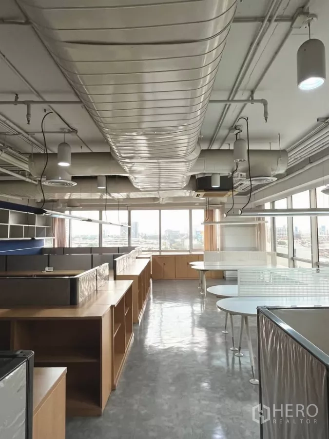 办公空间 出租在Khlong Toei, Bangkok - 明亮开放办公区，线型吊灯与管道空调，整面窗墙。