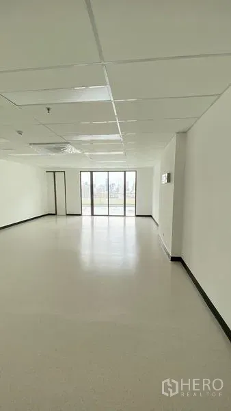Office Space for rent in Watthana, Bangkok - Bright open-plan office interior showing ceiling panels and wide glazed doors to the view.